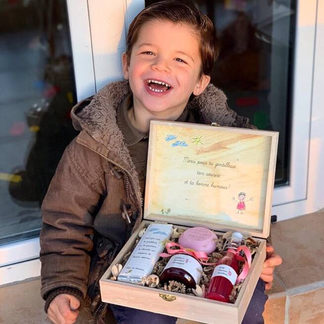 Un garçon tient une boîte en bois pour cadeau de fêtes de meres contenant 4 souvenirs