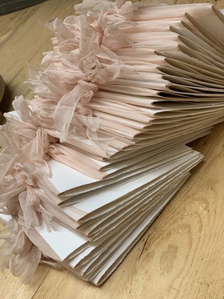 une pile de livrets de messes de mariage avec lacets en organza